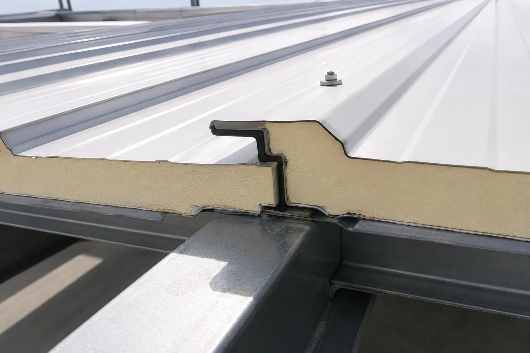 Sandwich roof panel side lap joint with sealing detail on a steel roof